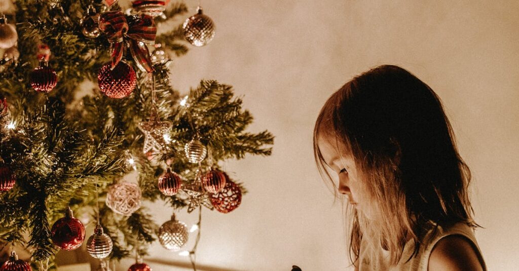 A young girl writes in a notebook by a Christmas tree adorned with decorations and lights.